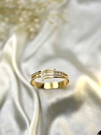 Elegant gold ring with Roman numeral design on cream satin background
