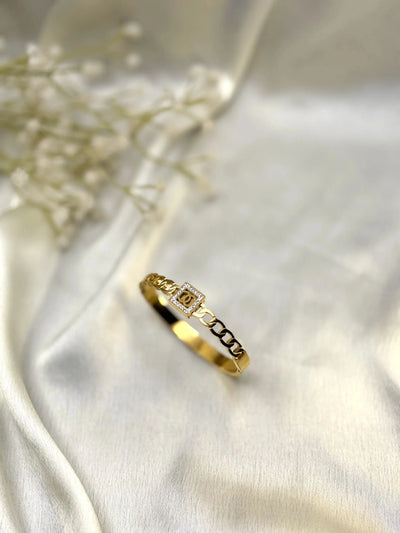 Gold chain bracelet with square diamond accent on cream satin fabric