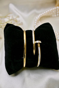 Gold bangles with diamond accents displayed on black velvet, elegant jewelry close-up