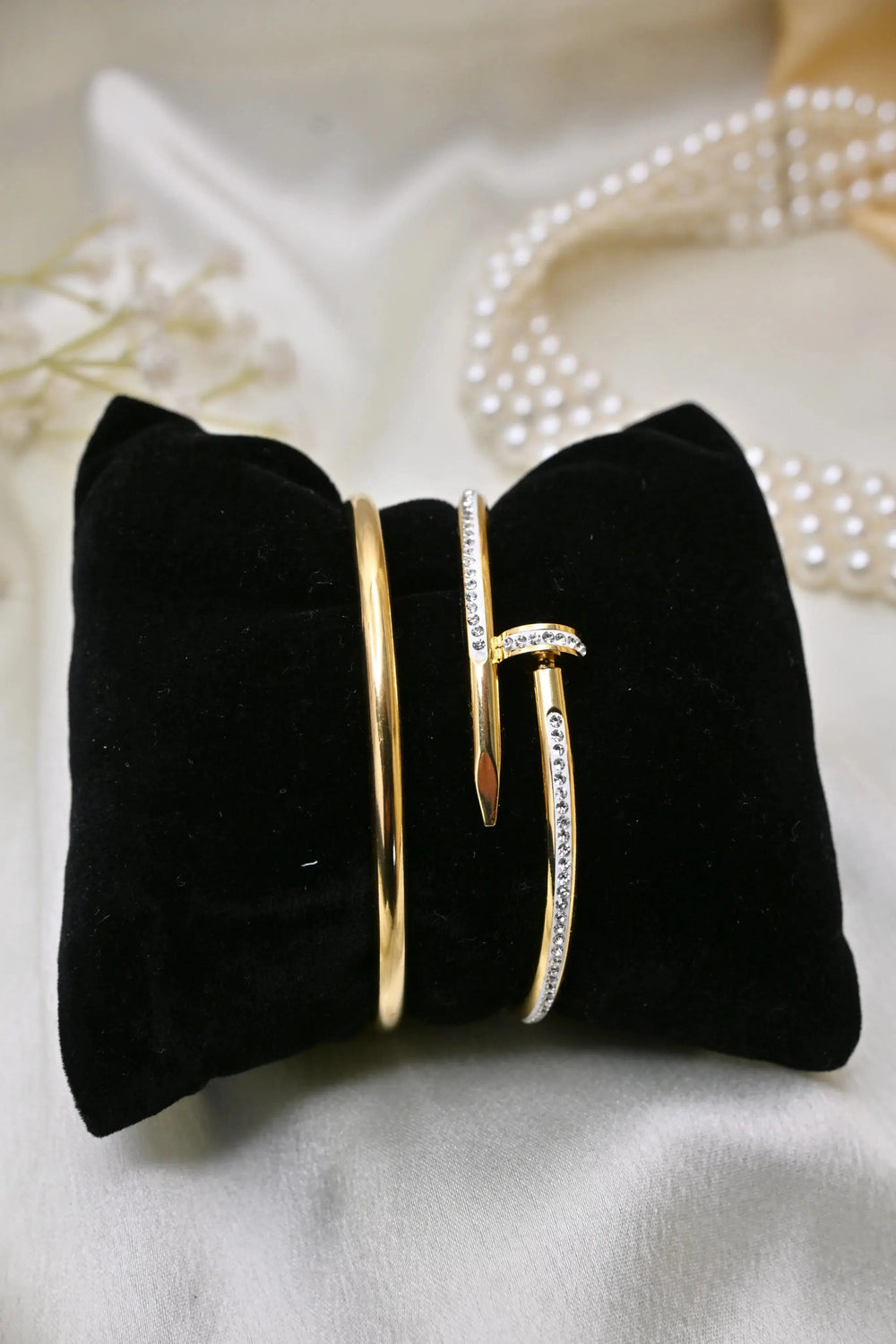 Gold bangles with crystal accents on black velvet display, elegant jewelry on satin background