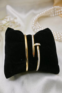 Gold bangles with crystal accents on black velvet display, elegant jewelry on satin background