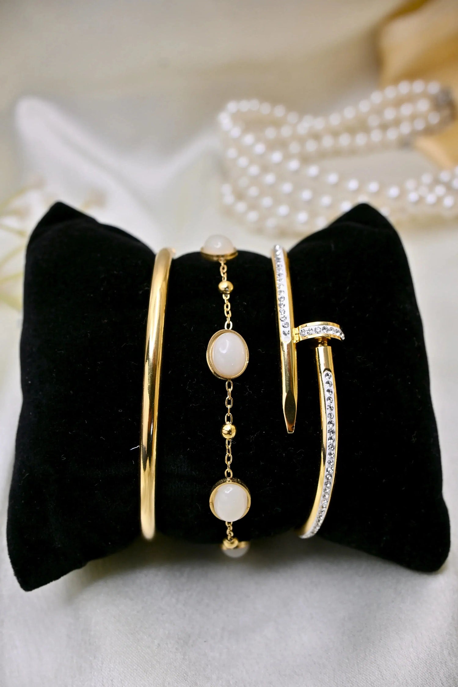 Gold bangles and bracelet with white stones and cubic zirconia accents on a black pillow