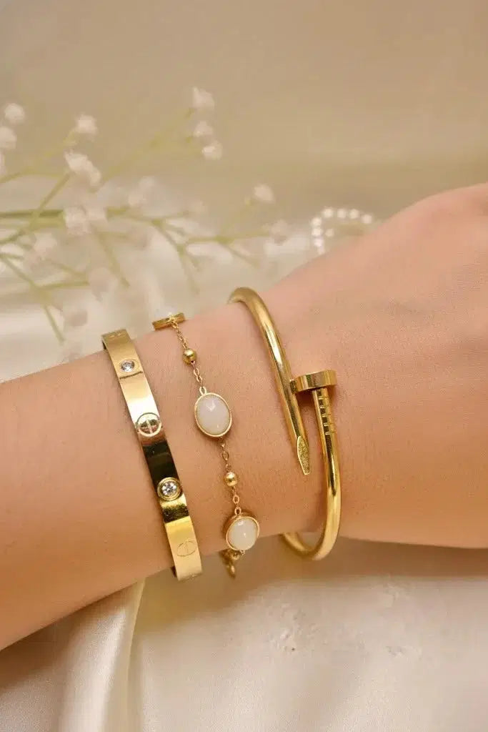 Elegant gold bangles and a delicate gold bracelet with white stones on a wrist