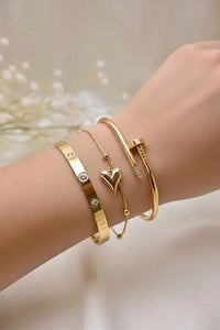 Woman's wrist adorned with elegant gold bracelets, including heart charm and diamond accents