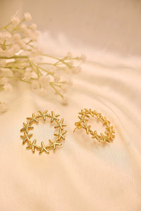 Gold starfish hoop earrings on a cream fabric background with white flowers
