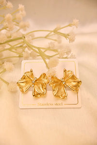 Gold flower-shaped stainless steel earrings with rhinestone centers on a display card