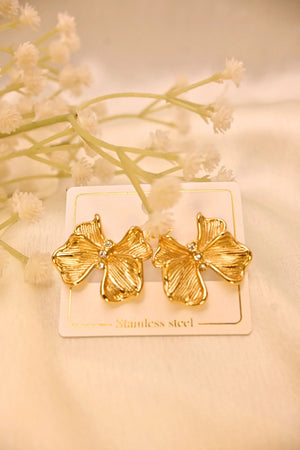 Gold flower-shaped stainless steel earrings with rhinestone centers on a display card