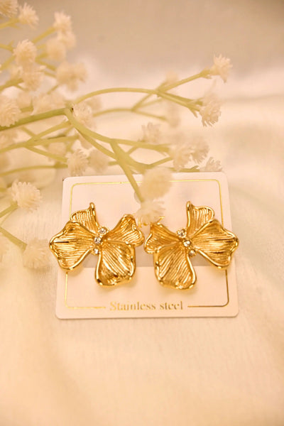 Gold flower-shaped stainless steel earrings with rhinestone centers on a display card