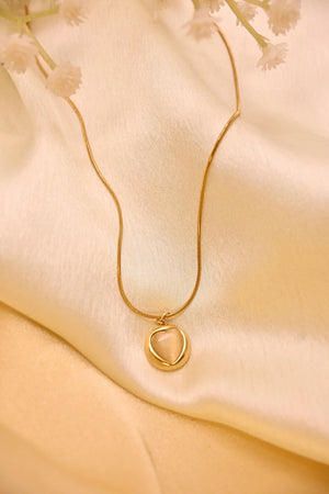 Delicate gold pendant necklace with minimalist design on a cream satin fabric