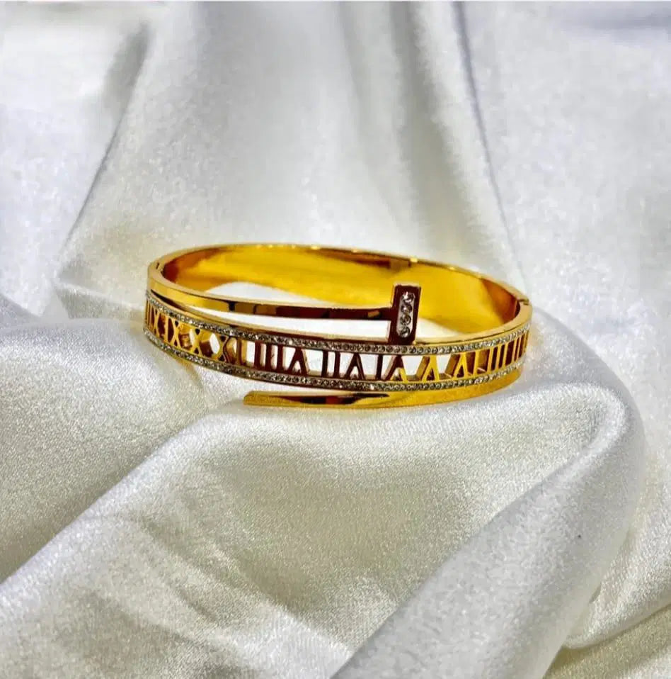 Gold bangle bracelet with Roman numerals and crystal accents on a satin fabric background