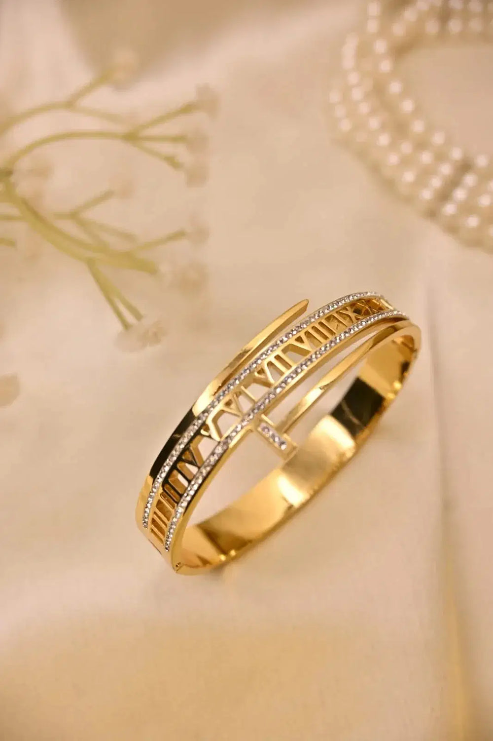 Gold bracelet with Roman numerals and diamond accents on a beige fabric background