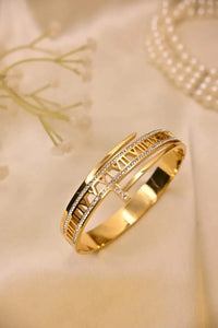 Gold bracelet with Roman numerals and diamond accents on a beige fabric background