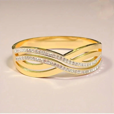 Gold bangle bracelet with crisscross design and embedded shimmering stones on a plain background